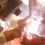 Welder welds with an electrode wearing gloves
